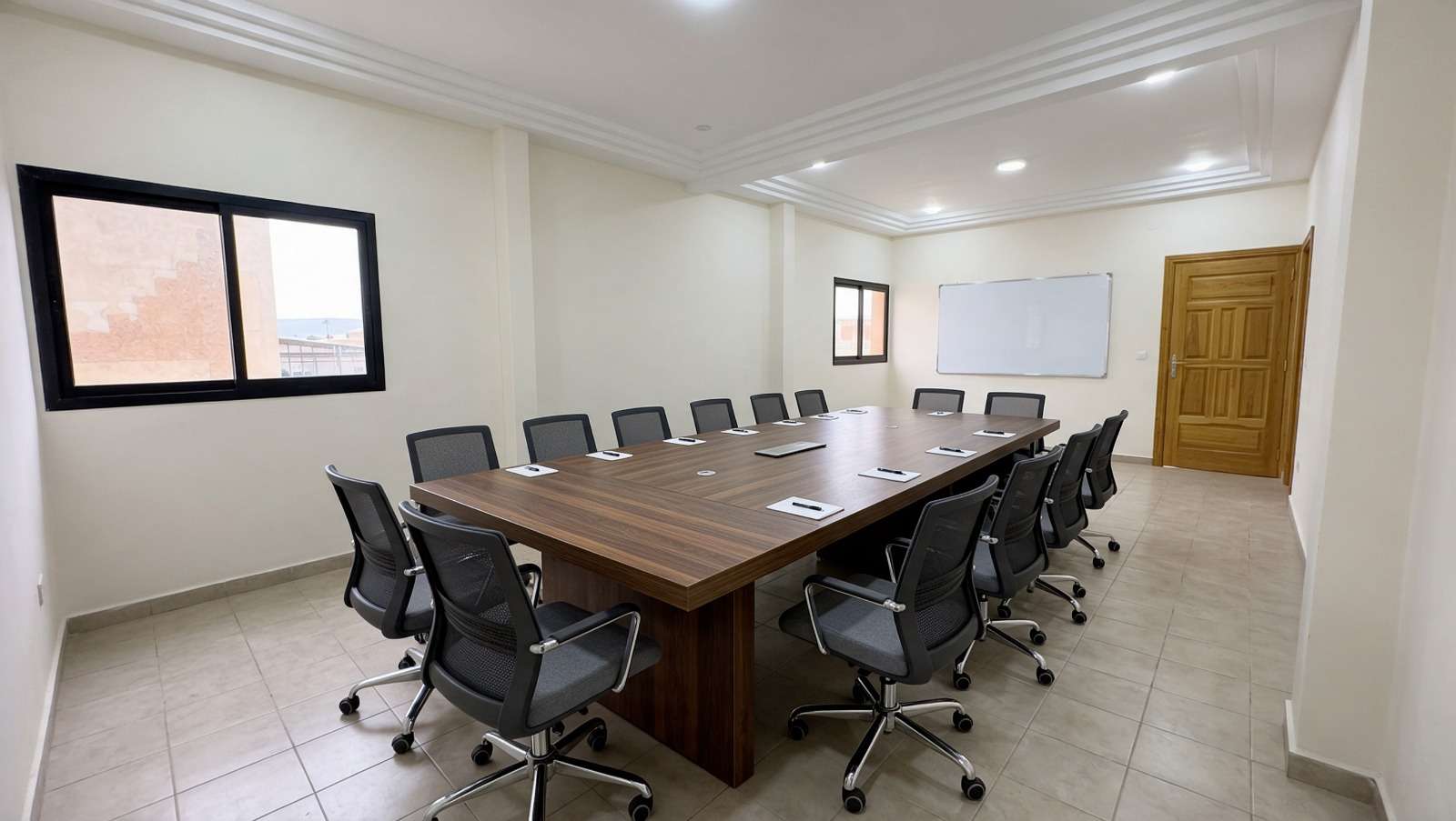 Salle de réunion avec une grande table en bois entourée de fauteuils.